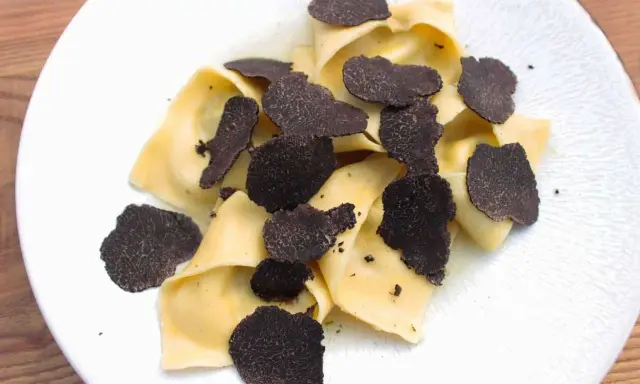 Délicieux raviolis frais garnis d'une généreuse quantité de lamelles de truffe noire. Un plat raffiné pour les amateurs de truffe.