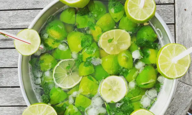 Un grand bol rempli de citrons verts, de menthe et de glaçons, prêt pour une recette mojito sans alcool 5 litres.