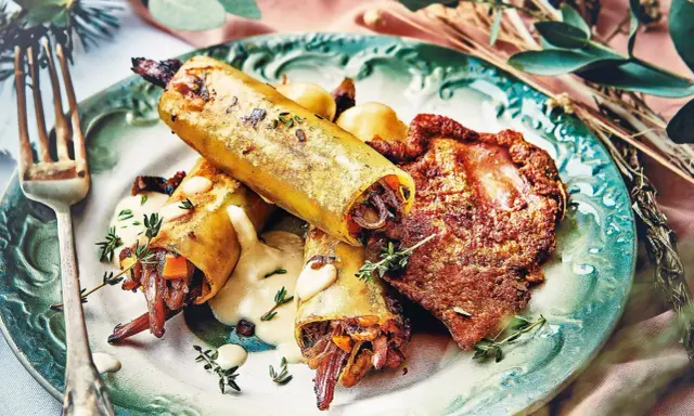 Un délicieux repas d'anniversaire léger : cannellonis farcis à la viande et légumes, accompagnés d'une sauce crémeuse et d'une tranche de viande croustillante.