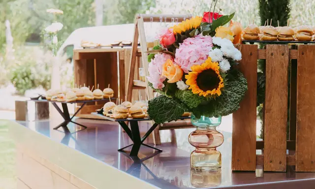 Un buffet de mini-burgers et un bouquet coloré, une belle idée apéro mariage en plein air.