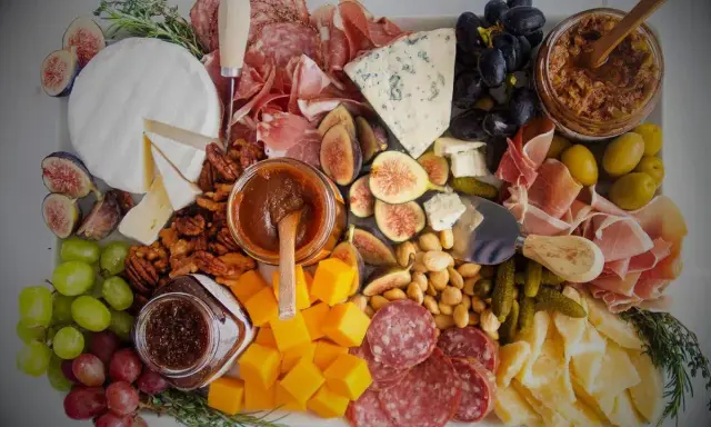 Plateau charcuterie et fromages : un buffet généreux avec jambon, saucisson, fromages variés, fruits, noix et confitures.