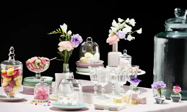 Buffet vin d'honneur fait maison : macarons colorés, meringues, guimauves et fleurs dans des vases.