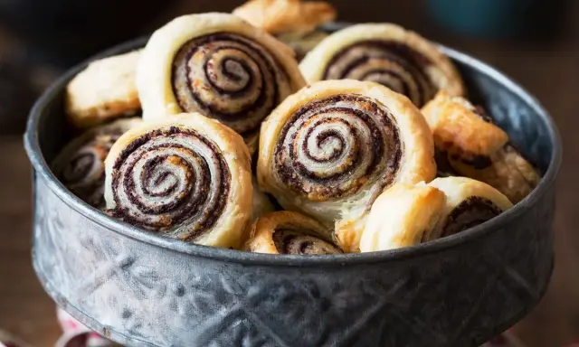 Un bol rempli de feuilletés tapenade, des roulés dorés à la pâte feuilletée croustillante et à la garniture sombre et savoureuse.