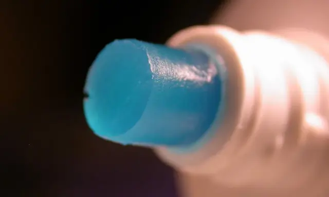 Goutte de dentifrice bleu sortant d'un tube blanc, parfaite pour polir l'aluminium.
