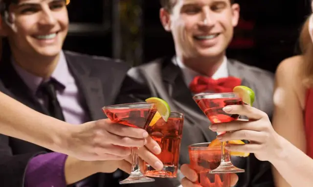 Des amis célèbrent avec des cocktails rouges, des rondelles de citron vert et d'orange. Une soirée de jeux du goût et de bonne humeur.