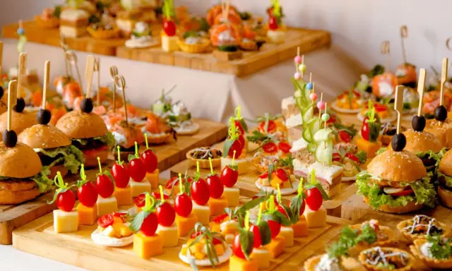 Buffet de petits fours variés : mini-burgers, toasts au saumon, brochettes de tomates et dés de fromage. Une belle idée pour une recette petit four réussie.