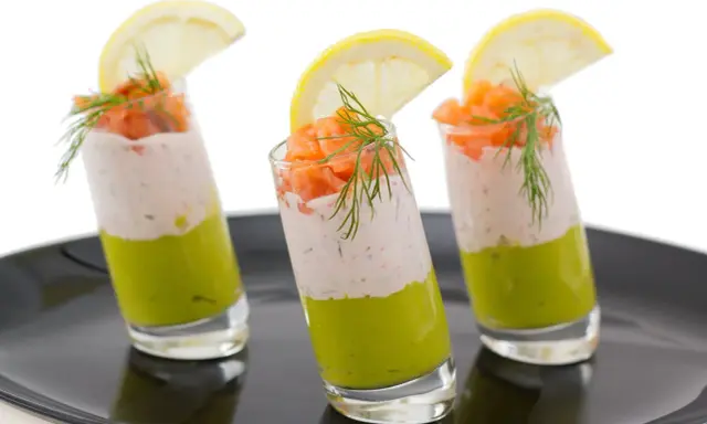 Trois verrines végétariennes colorées, garnies de saumon, d'une crème légère et d'une tranche de citron.