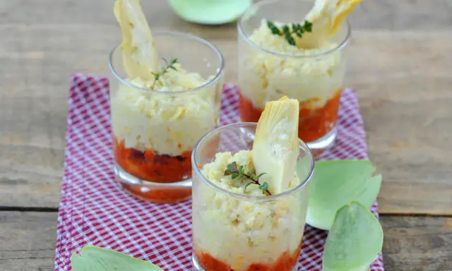 Trois verrines artichaut, garnies d'une purée crémeuse et d'une touche de sauce tomate, sur un fond de bois rustique.