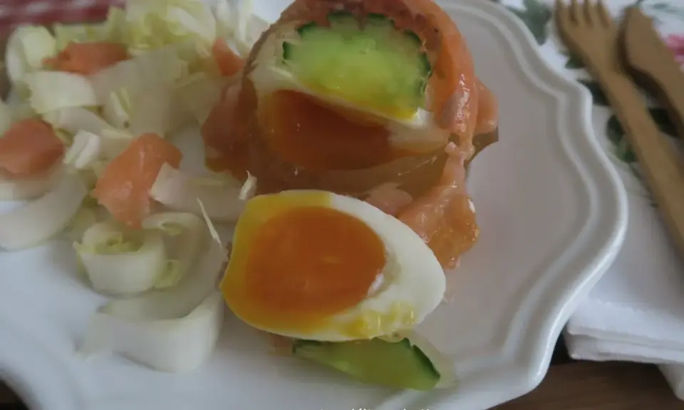Un œuf en gelée au saumon, garni de concombre et servi avec des dés de saumon fumé et des endives. Un délice !