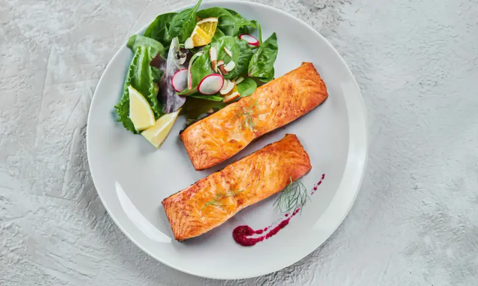 Deux pavés de saumon au four, accompagnés d'une salade fraîche et de quartiers de citron. Un délice simple et savoureux.
