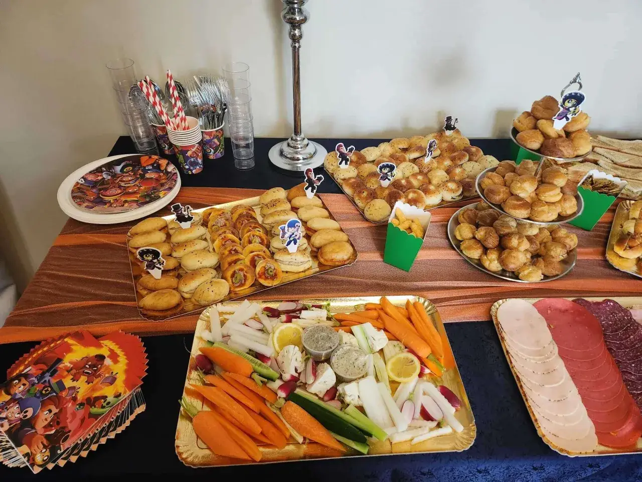 Un délicieux buffet froid avec des petits pains, des crudités, des dips et de la charcuterie, parfait pour une fête d'enfants.