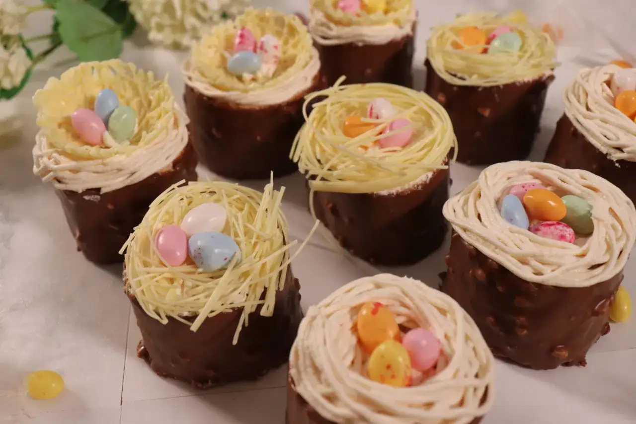 Délicieux dessert de Pâques traditionnel : petits nids en chocolat garnis de vermicelles et d'œufs colorés.