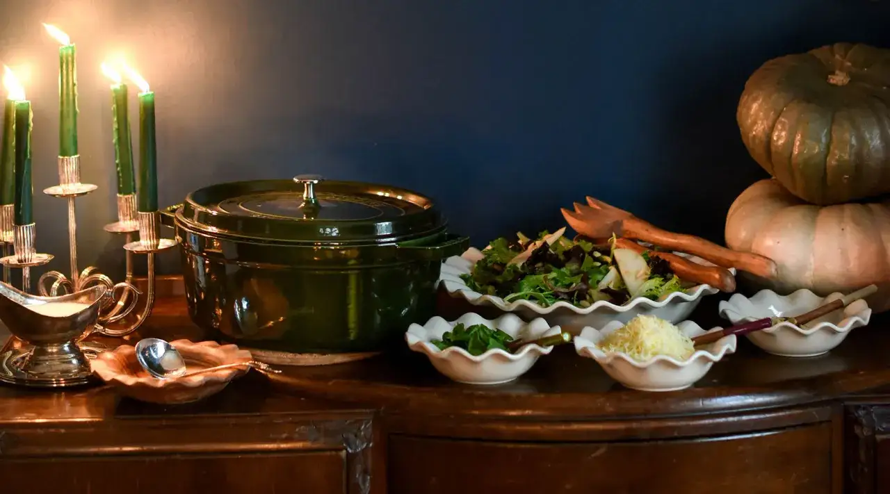 Belle organisation buffet : salade, gratin, sauce, bougies vertes et citrouilles.