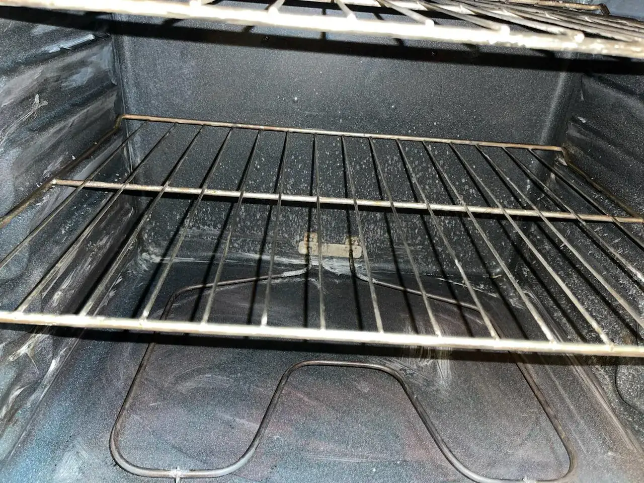 Intérieur d'un four, avec une grille métallique et des traces blanches de décap four sur les parois.