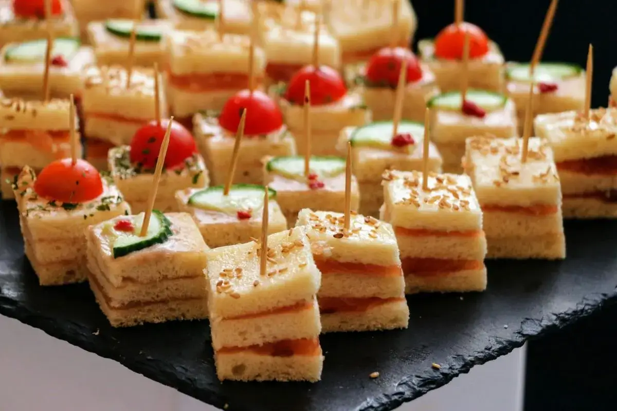 Petits sandwichs carrés, garniture saumon ou concombre, tomates cerises. Parfait pour un apéritif finger food.