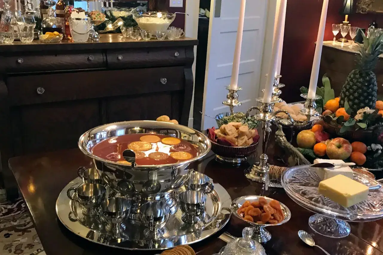 Un grand bol de punch aux fruits, garni de rondelles d'orange, pr&ecirc;t pour une recette de punch sans alcool pour 30 personnes. Fruits, biscuits et bougies sur la table.