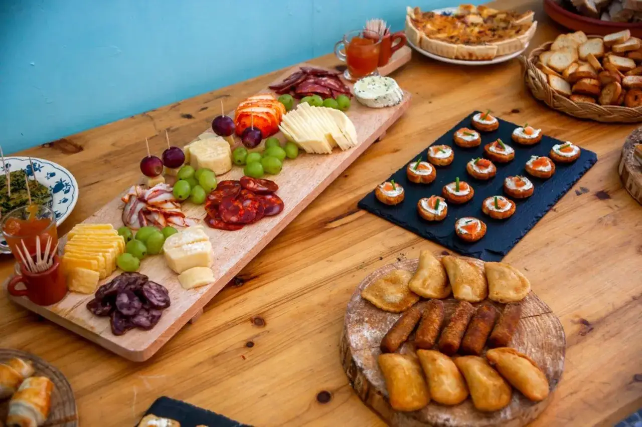 Un buffet campagnard pour 20 personnes : planches de charcuterie, fromages, raisins, mini-quiches, toasts au saumon et feuilletés.