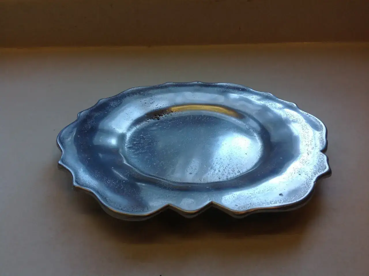 Assiette en aluminium ternie, prête pour un polissage au dentifrice pour lui redonner son éclat.