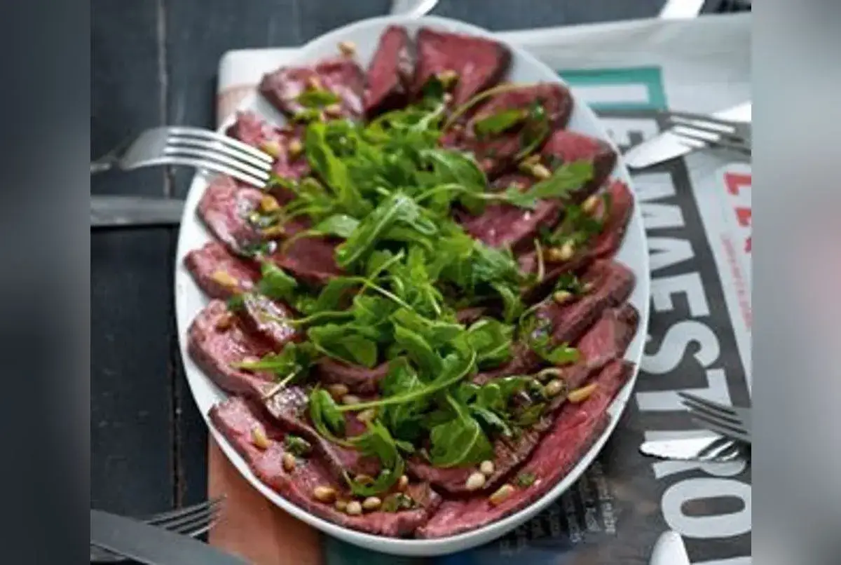 Un rôti de boeuf froid pour 20 personnes, finement tranché, garni de roquette fraîche et de pignons de pin. Un délice pour les grandes tablées.