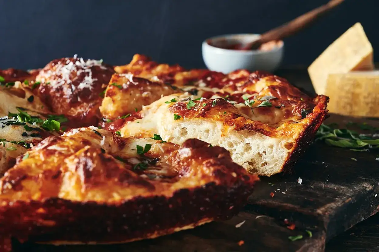 Une pizza maison, dorée et croustillante, témoigne de la parfaite cuisson pizza au four. Le fromage fondu et les herbes fraîches invitent à la dégustation.