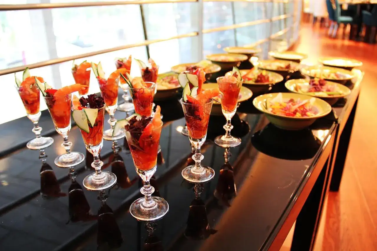 Petits verres garnis de crevettes et crudit&eacute;s, pr&ecirc;ts pour un ap&eacute;ritif dinatoire.