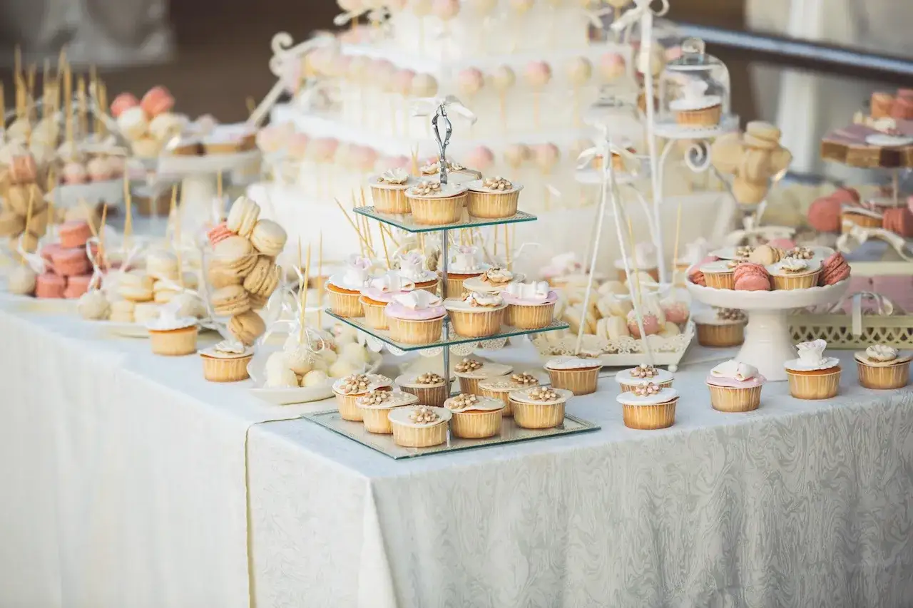 Un magnifique buffet dessert baptême, rempli de cupcakes, macarons et autres douceurs, prêt à célébrer un événement spécial.