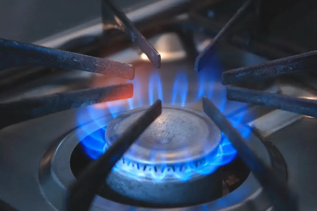 Flamme bleue sur un brûleur de gazinière, les grilles chauffent. Un défi pour nettoyer graisse brûlée gazinière.