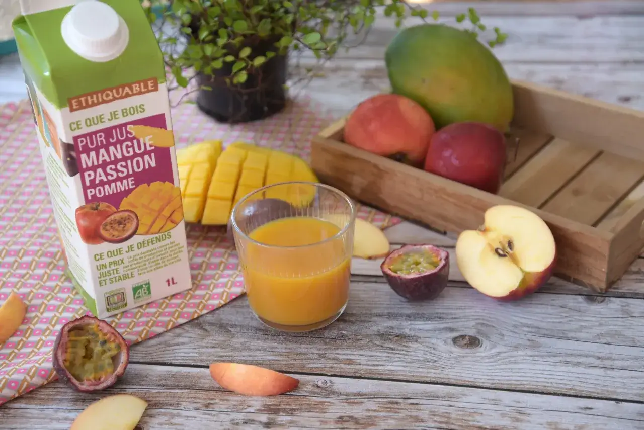 Un verre de jus mangue-passion-pomme, le meilleur jus de fruit, &agrave; c&ocirc;t&eacute; de fruits frais et d'une brique de jus.