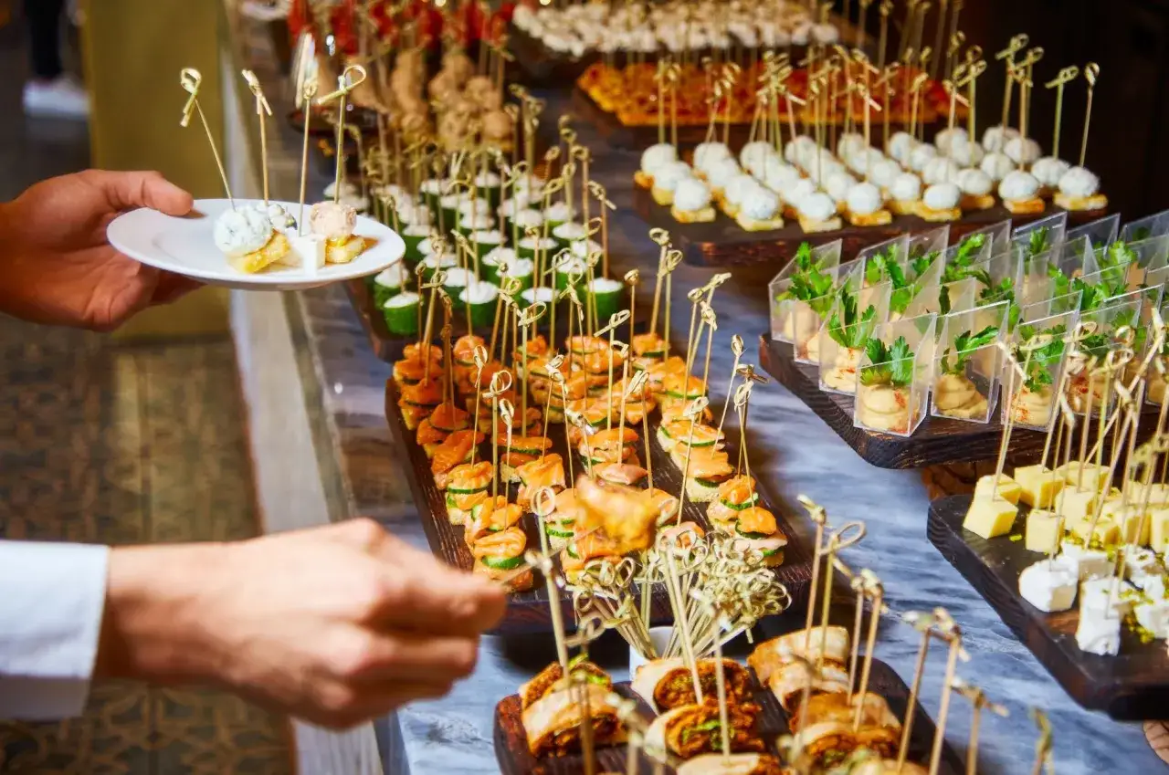 Un buffet varié pour un repas d'anniversaire original et pas cher : mini-sandwichs, verrines, brochettes de saumon et plateau de fromages.