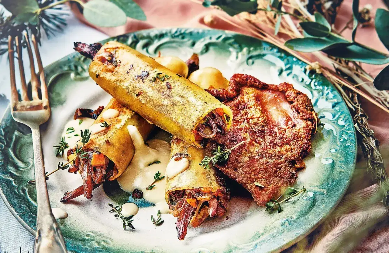 Trois rouleaux dorés farcis de viande et légumes, accompagnés d'une sauce crémeuse et d'une tranche de viande croustillante. Un repas d'anniversaire léger et savoureux.