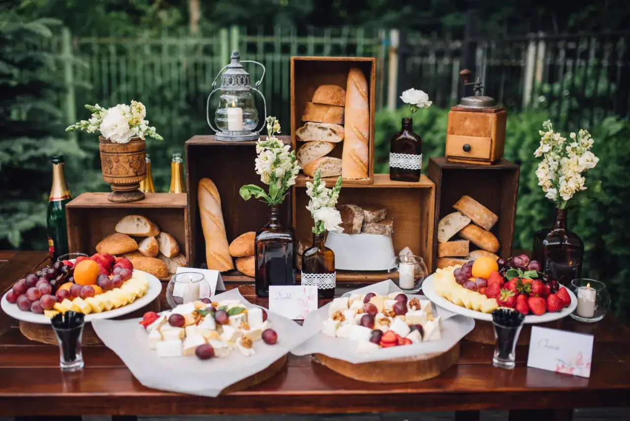 Un buffet champêtre avec pains, fromages, fruits et fleurs. Une belle présentation rustique.