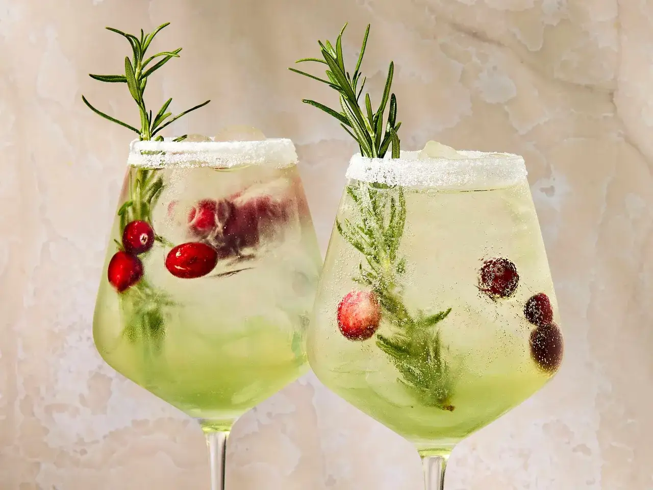 Deux cocktails pétillants avec des canneberges et du romarin, parfaits pour savoir que boire à l'apéro.