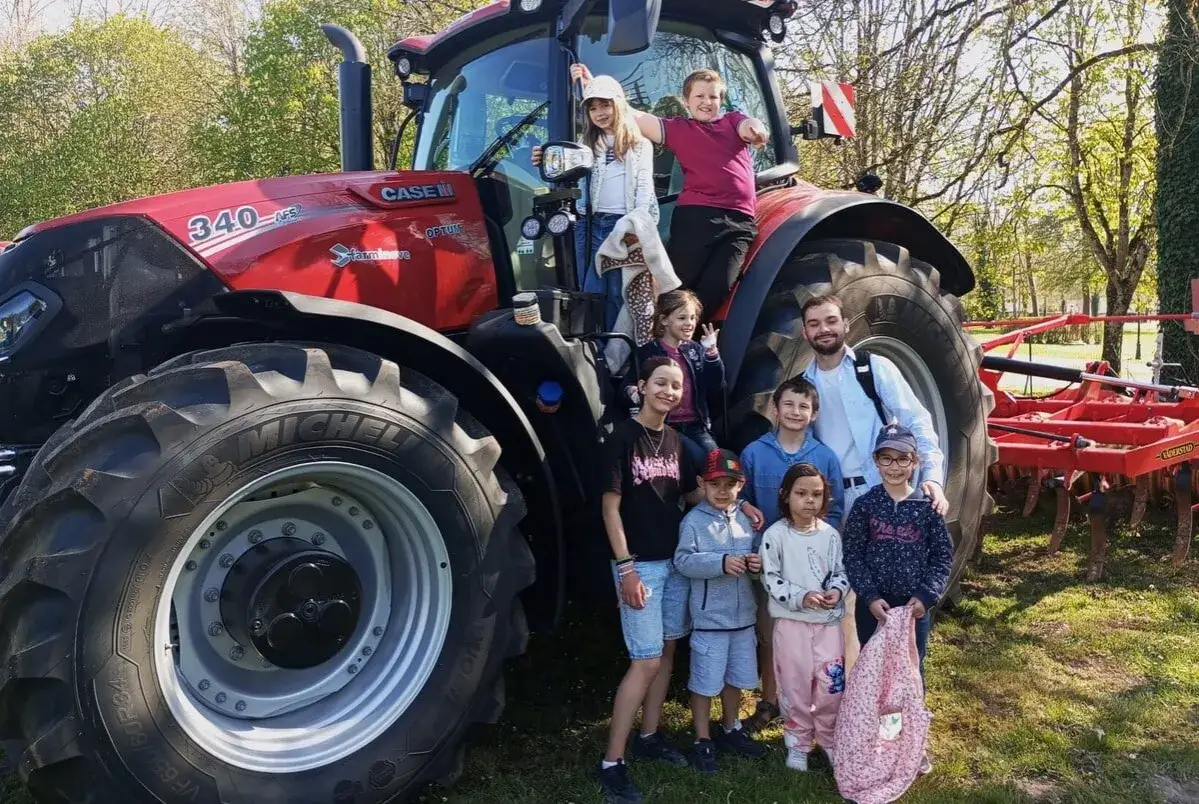 Une joyeuse bande d'enfants participe &agrave; un rallye photo enfant, posant devant un gros tracteur rouge.