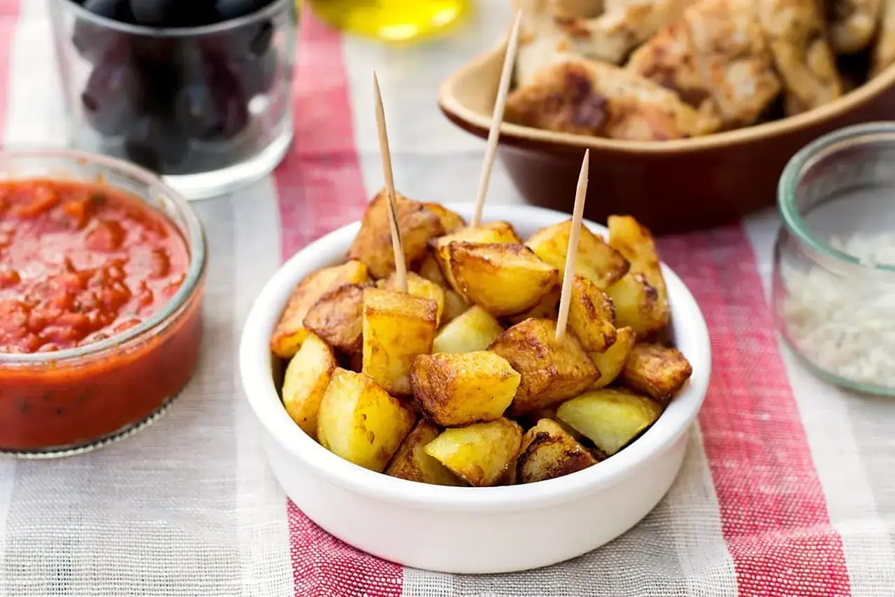 Patatas bravas dor&eacute;es, servies avec une sauce piquante et des olives noires. Un d&eacute;lice pour les tapas !