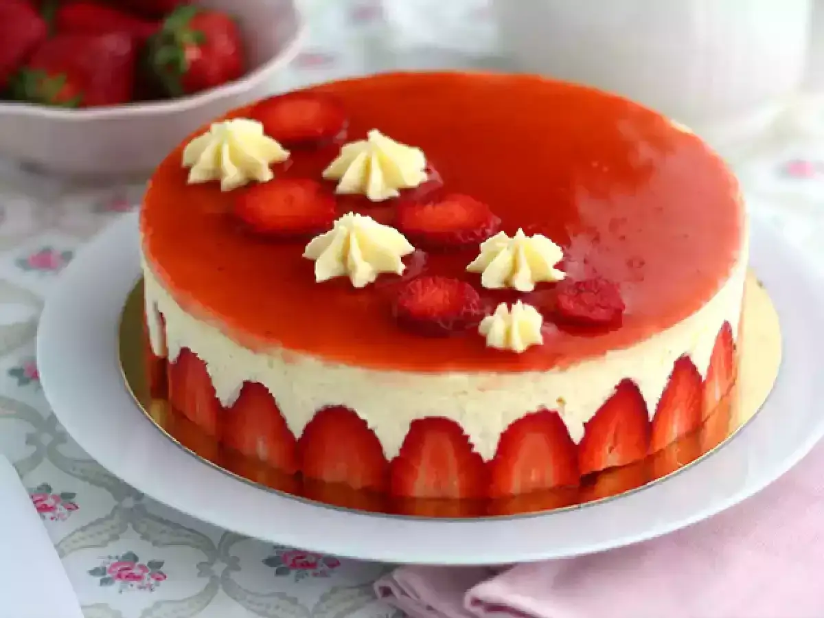 Un magnifique gâteau fraise, nappé d'un glaçage rouge brillant et décoré de fraises fraîches et de crème.
