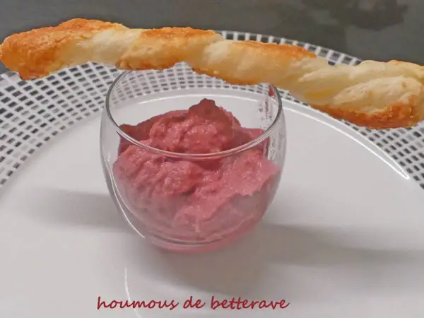Un verre de houmous de betterave, garni d'un bâtonnet de pâte feuilletée croustillant. Une touche colorée et savoureuse pour l'apéritif.
