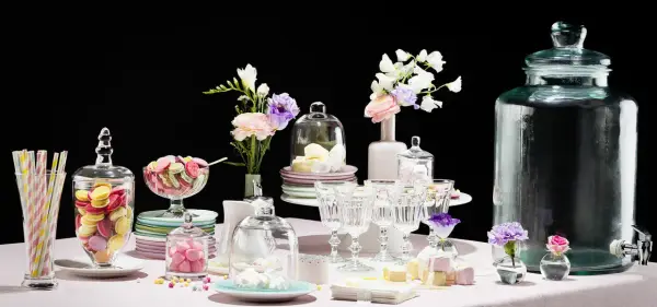 Buffet vin d'honneur fait maison : macarons colorés, meringues, guimauves et fleurs dans des vases.